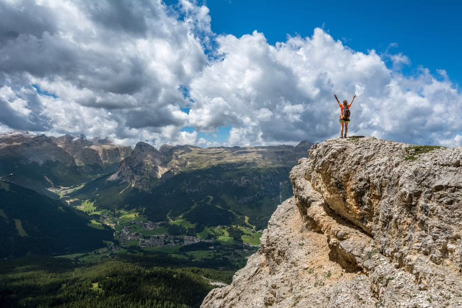 Image of a woman standing on a cliff overlooking mountains.