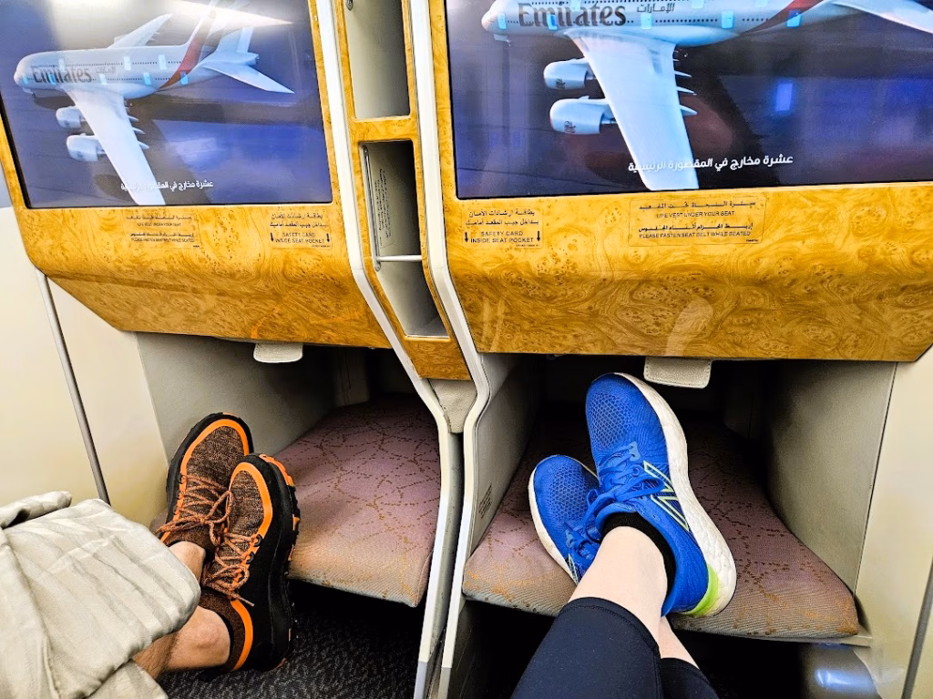 Two people propping up their feet in the seat of Emirates business class 