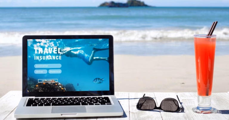 A beach in the background with sunglasses, a bright red drink and a laptop reading Travel Insurance.