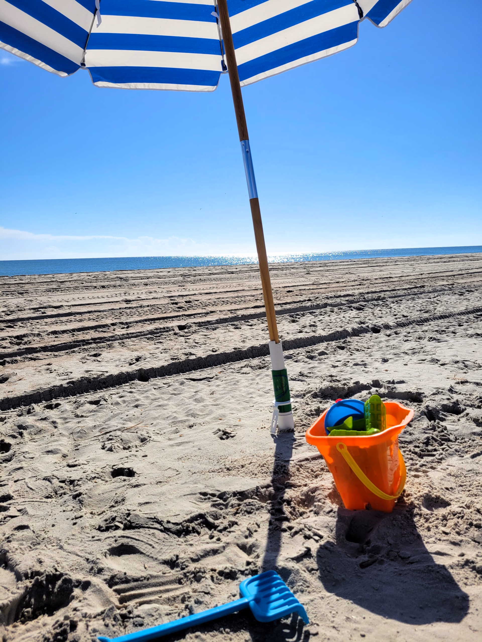 Beach with blue and white umbrella and sand toys at Indian Beach, NC.
