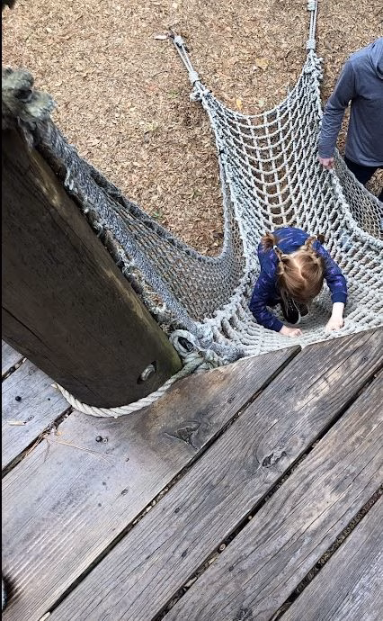 Girl with two braids climbing the rope wall at the North Carolina Aquarium at Pine Knoll Shores.