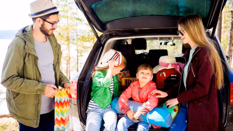Family of four with two young girls sitting in back of car, ready for a road trip.