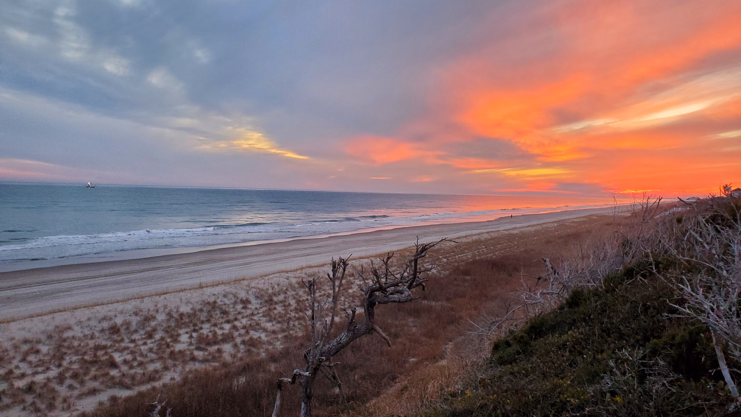 dune in front of ocean at indian beach with orange sky in background